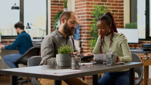 Friends using laptop while sitting on table