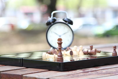 Close-up of clock with chess board on table