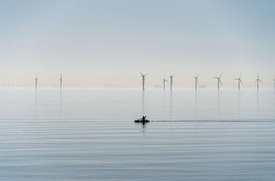 Offshore wind turbines generating renewable electricity and energy  atmospheric background image