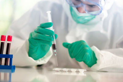 Smiling doctor wearing protective mask standing in laboratory