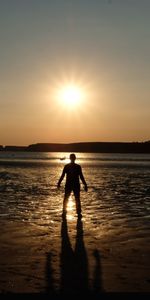 Silhouette man on beach against sky during sunset