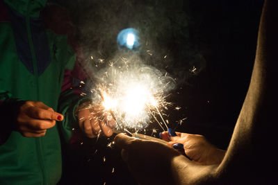Midsection of friends holding sparklers 