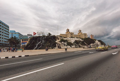 View of city street against cloudy sky