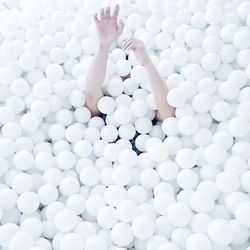 Cropped image of hand emitting from white ball pool