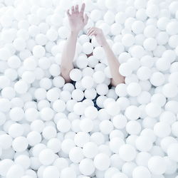 Cropped image of hand emitting from white ball pool