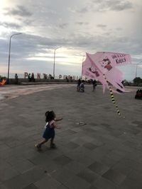 People on footpath in city against sky