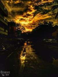 Cars on street in city against sky at sunset