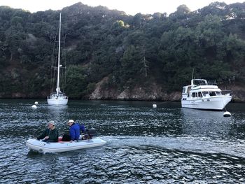 Boat sailing on river by tree mountain