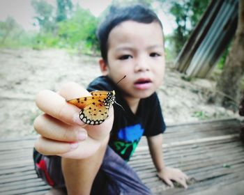 Portrait of boy holding butterfly