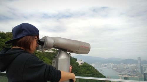 Woman standing by cityscape against sky