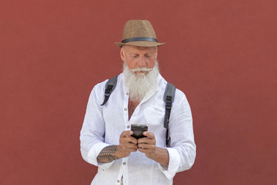 Portrait of man wearing hat against red background