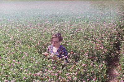 Woman standing by flowering plants on field