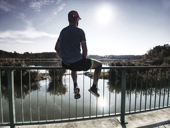 Sportsman is sitting on handrail in the park. feet of jogging man. sunny morning, sport concept