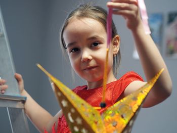 A little girl in a festive red dress is busy decorating the room with a paper gold star. new year 