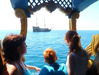 People traveling in ship on sunny day