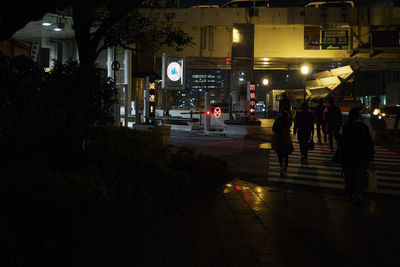 People walking on illuminated street at night