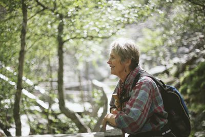 Side view of smiling young woman in forest