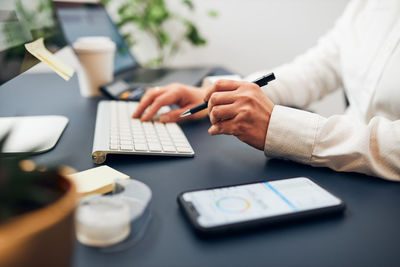 Midsection of man using mobile phone on table