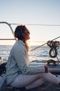 Side view of woman looking at sea against sky