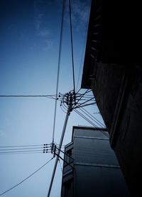 Low angle view of electricity pylon and building against sky