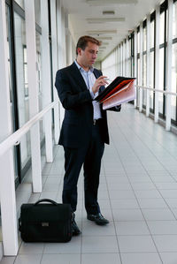Businessman standing with documents at office corridor