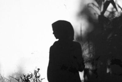 Rear view of silhouette woman standing against wall