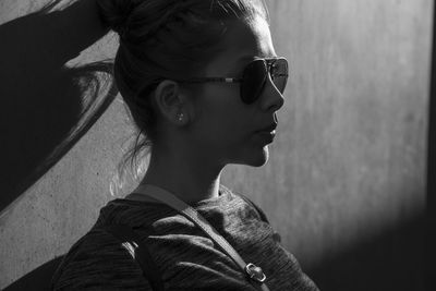 Woman wearing sunglass by wall