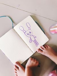 Low section of girl by book with drawing on floor