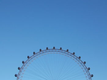 Low angle view of ferris wheel against clear blue sky