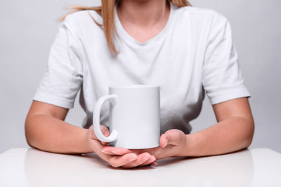 Midsection of woman holding coffee cup on table