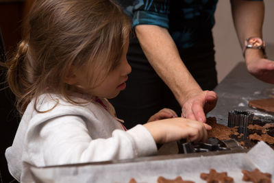 Girl preparing cookie with mother on kitchen island at home