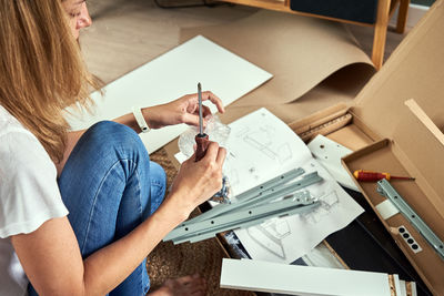 Woman reading manual instruction to assemble furniture