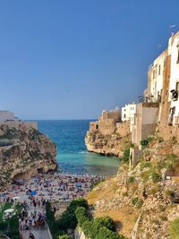 Buildings by sea against clear blue sky