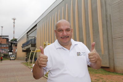 Portrait of man with arms raised standing in front of building