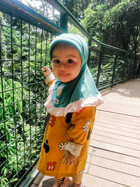 Portrait of cute girl standing against railing