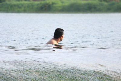 Side view of shirtless man in lake