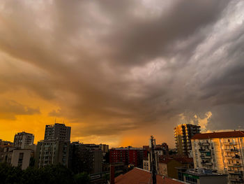 Buildings against dramatic sky during sunset