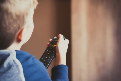 Close-up of kid changing channels with remote control while watching tv.
