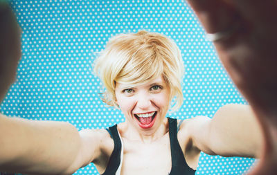 Portrait of smiling woman against blue curtain