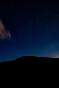 Low angle view of silhouette mountain against sky at night