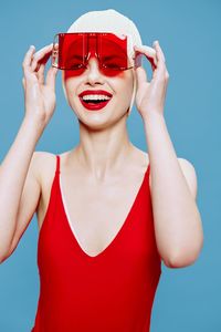 Low angle view of young woman wearing sunglasses against blue background