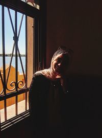 Smiling woman standing by window at home