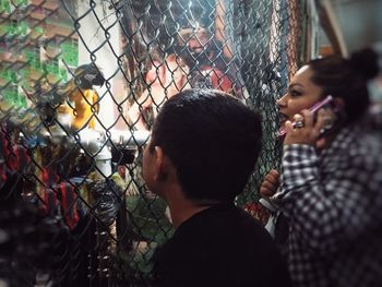 Rear view of father and daughter by chainlink fence