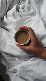 Midsection of woman holding coffee cup on bed