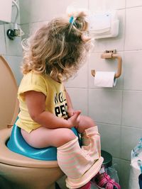 Rear view of girl sitting in bathroom