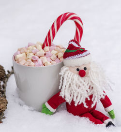 Close-up of santa claus toy with marshmallows on fake snow