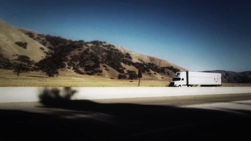 Road leading towards mountains against clear sky