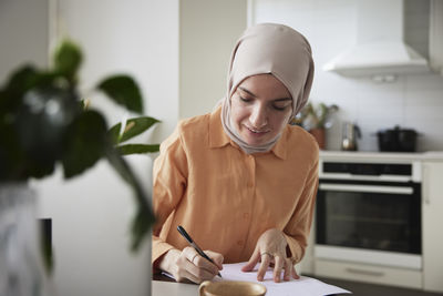 Smiling woman with hijab working at home