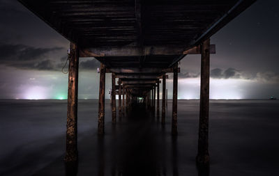 Silhouette of pier on beach against sky