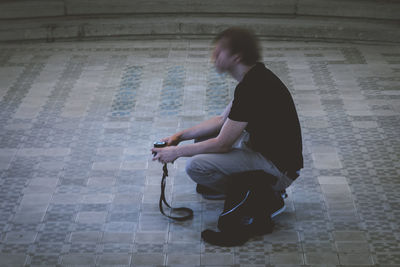 Man holding camera crouching on tiled floor